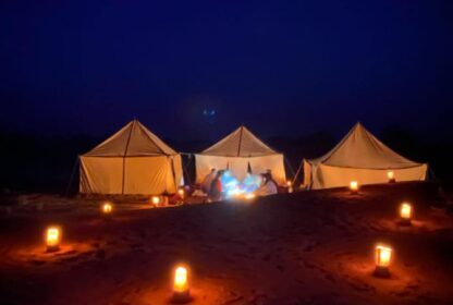 Grain de Sable du Maroc - bivouac nomade sous une nuit étoilée dans le désert - groupe de personnes assis autour du feu de camp