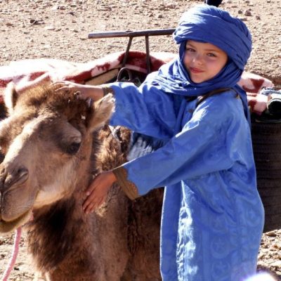 Trek en famille - un petit garçon avec un dromadaire - Grain de sable du Maroc